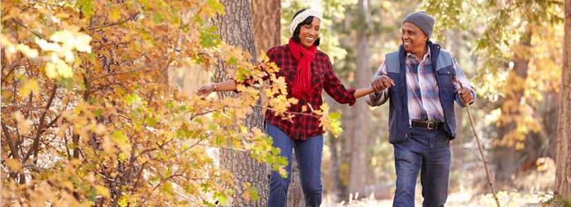 older couple with walking sticks walking in woods