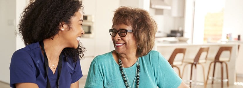 nurse talking to patient sitting at kitchen table