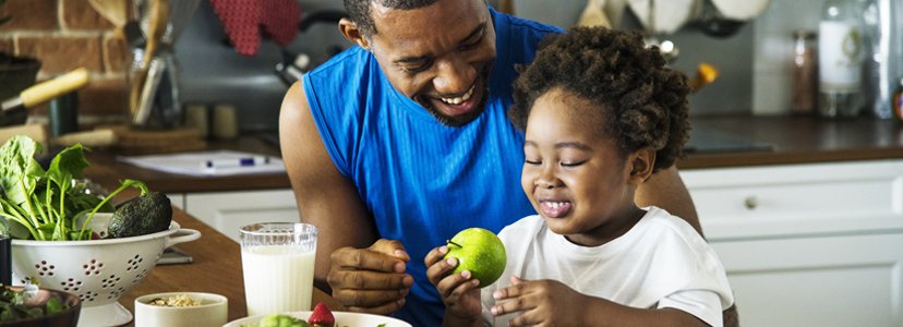 father showing toddler son an apple