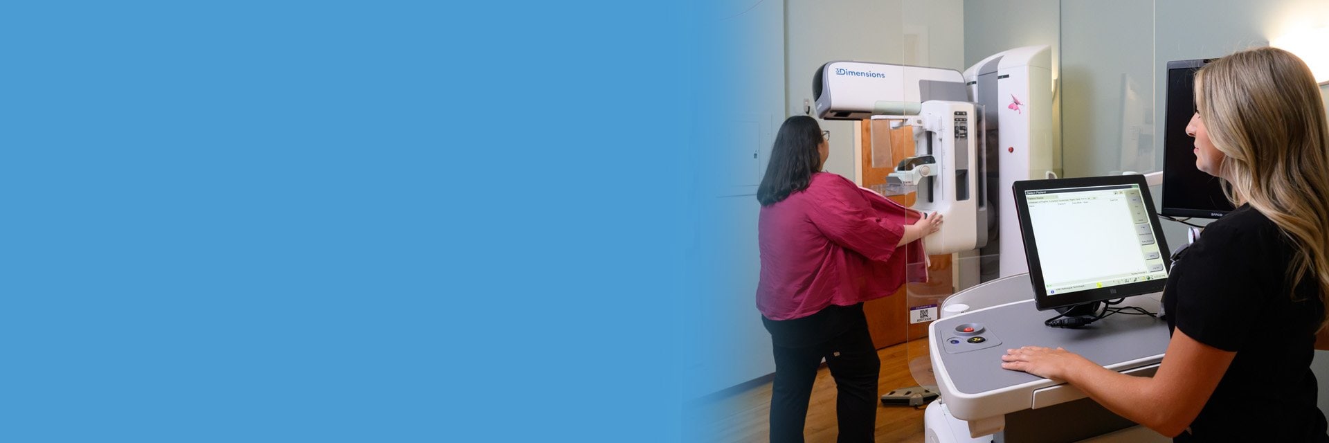 Woman gets a mammogram while nurse stands at a computer at the work station.