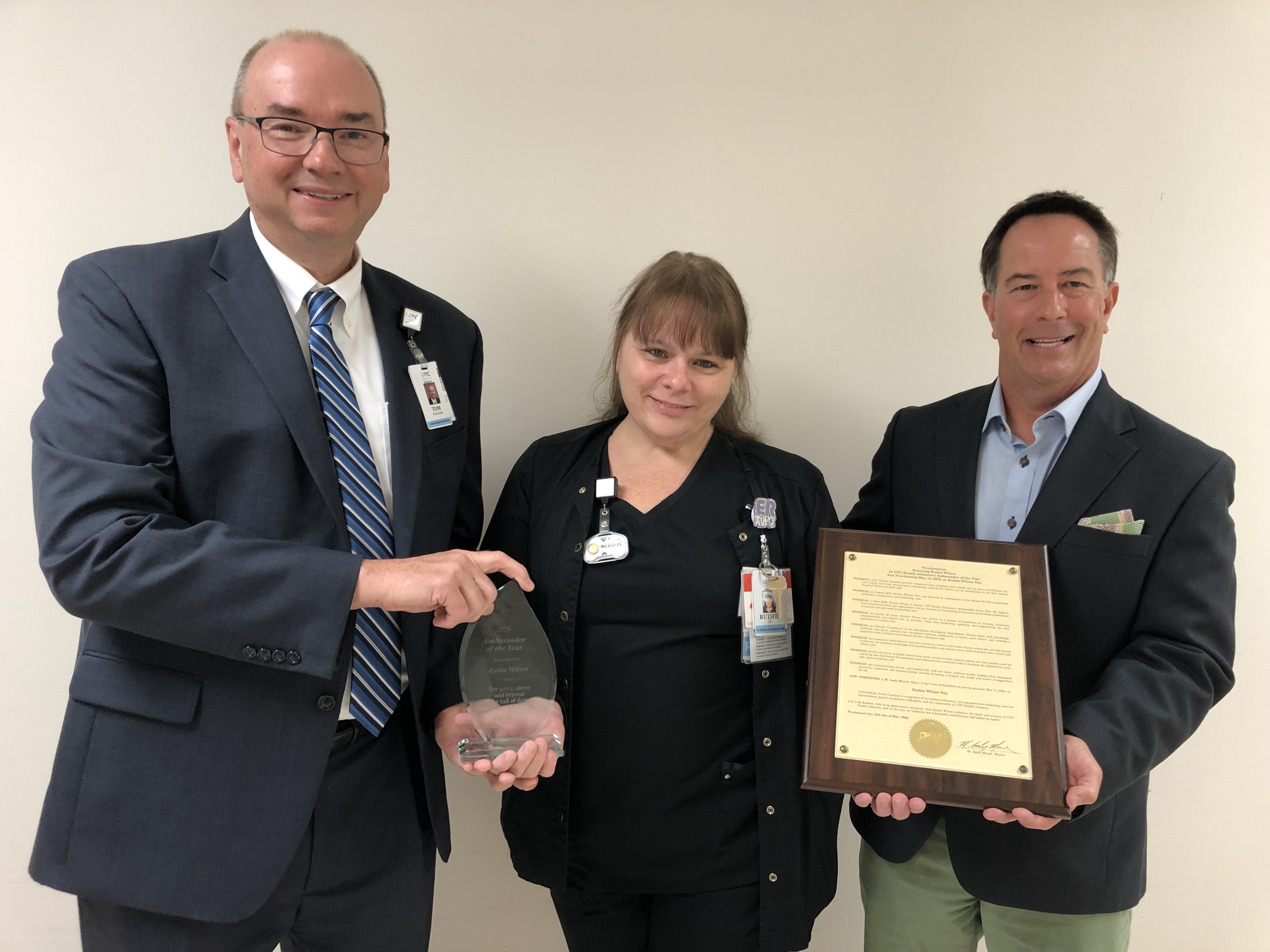 CEO Tom Williams presents a trophy and Smithfield Mayor Andy Moore proclaims a special day to honor and recognize Ruthie Wilson as UNC Health Johnston’s Ambassador of the Year.